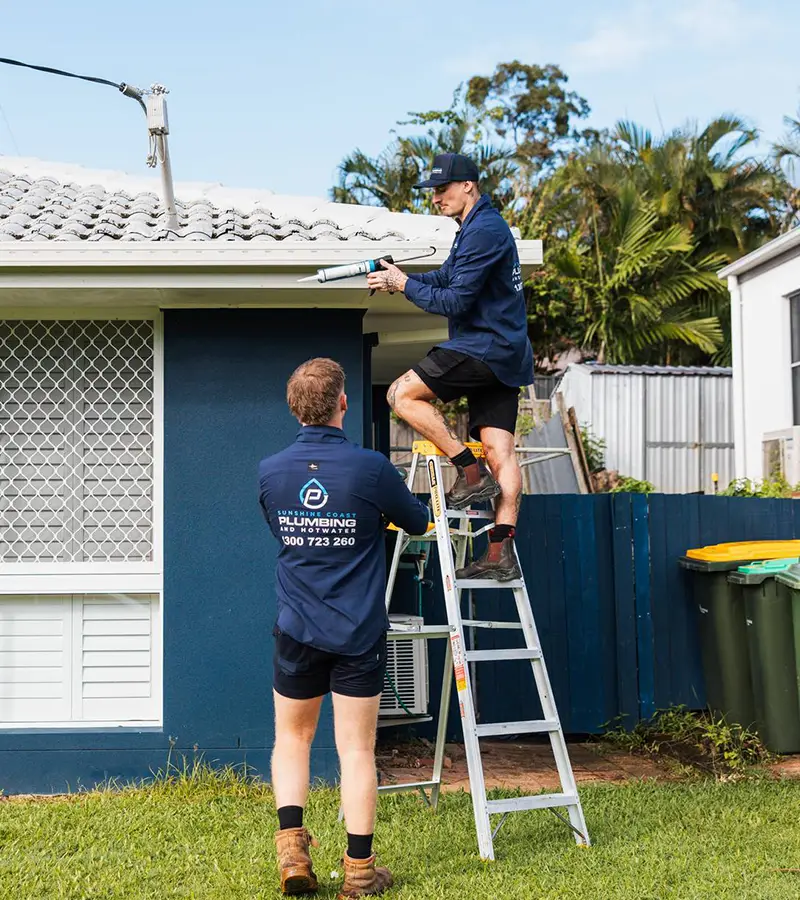 Plumber clearing a roof gutter and downpipe
